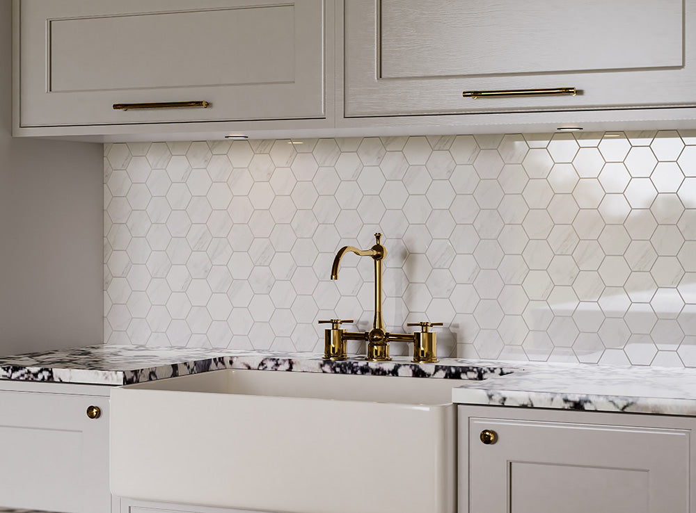 Kitchen with white hexagonal tile backsplash, gold faucet, and marble countertop.