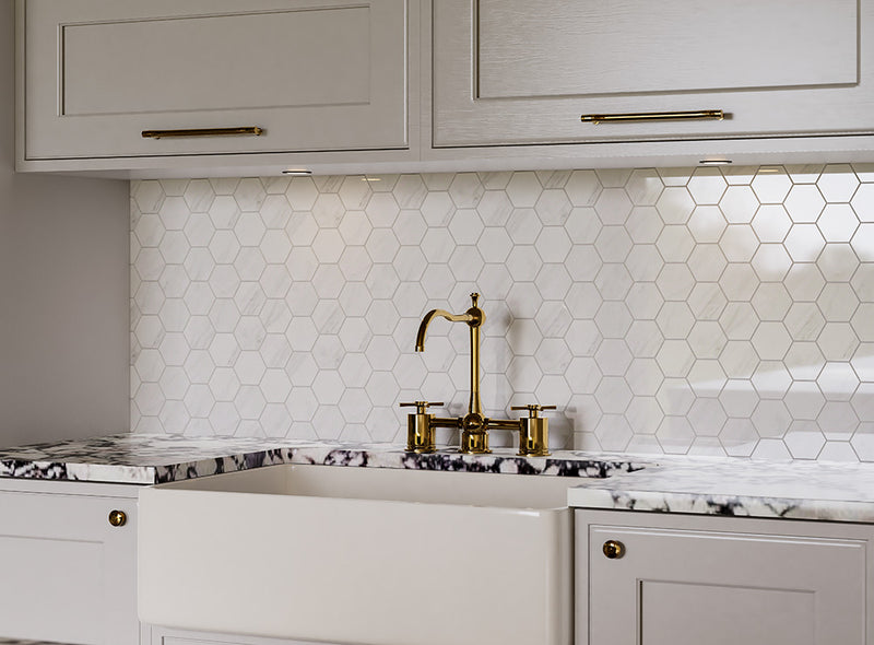 Kitchen with white hexagonal tile backsplash, gold faucet, and marble countertop.