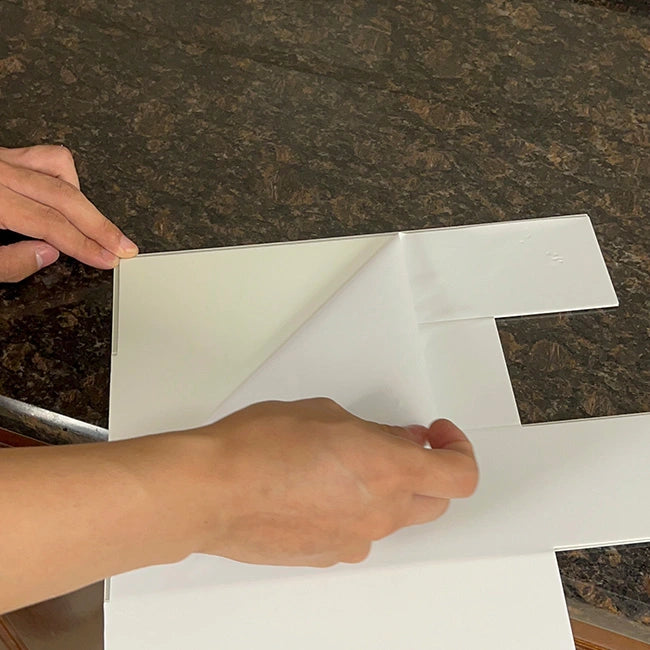 Peeling backing paper from self adhesive concrete backsplash tile before installation